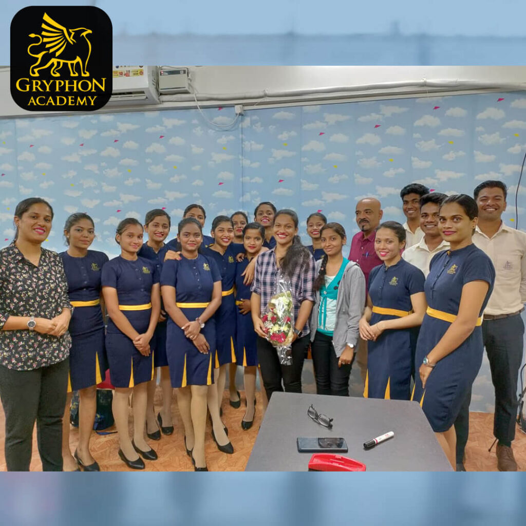 Group photo of Gryphon Academy team members and students in uniform, standing together in a classroom. The Gryphon Academy logo is displayed in the top-left corner.